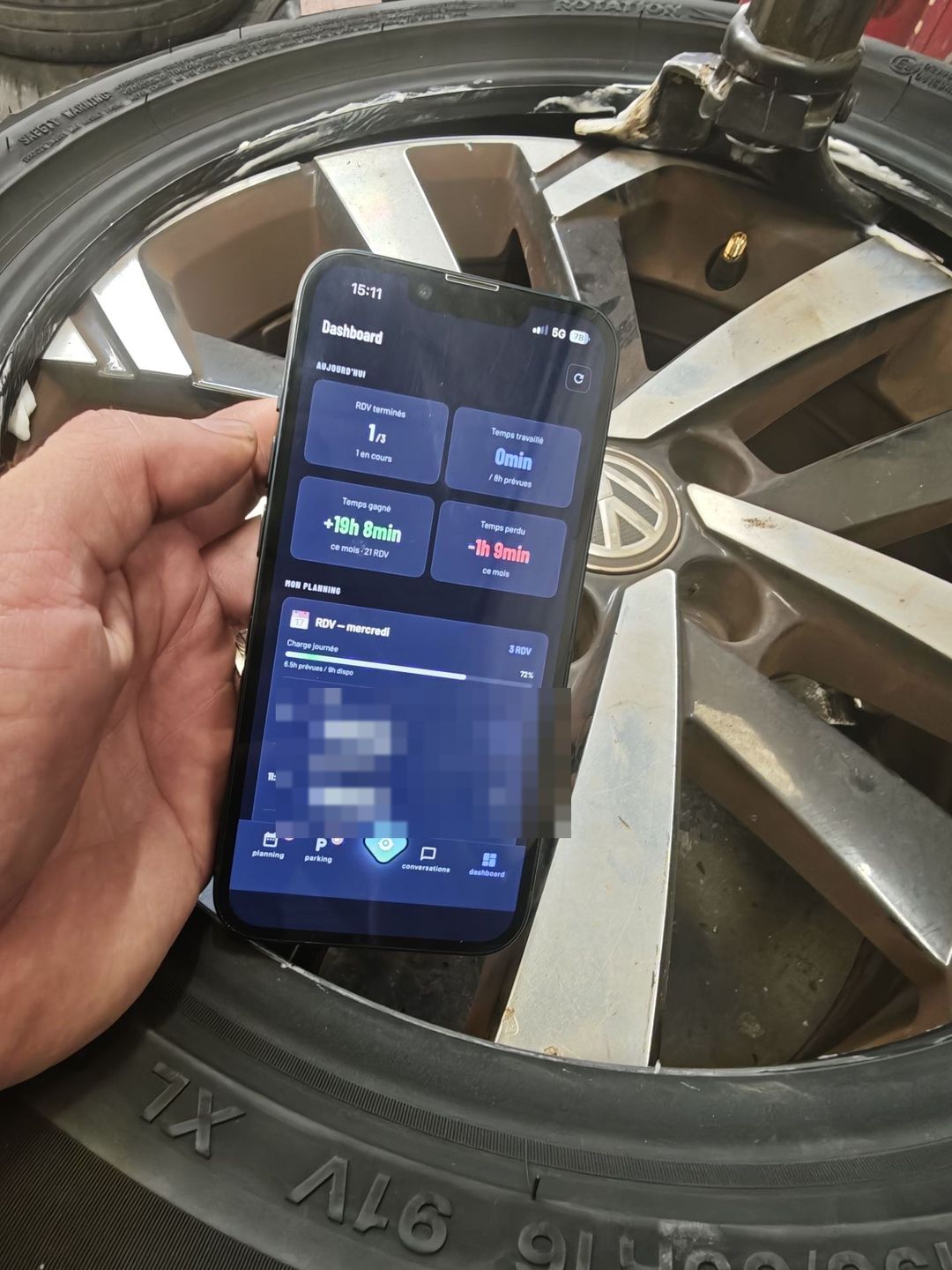 Application technicien Axium en mode sombre, posée sur une jante dans l'atelier : dashboard avec 19 h 08 de temps gagné sur le mois